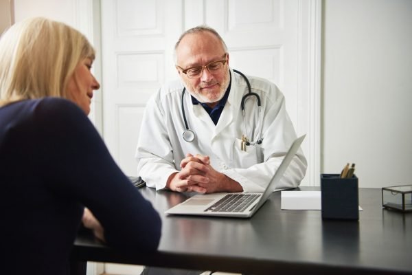 Medic and patient at laptop in office